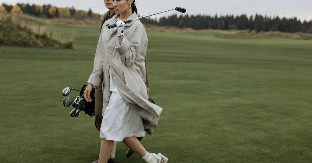 A fashionable couple walking with golf equipment on a lush green course.