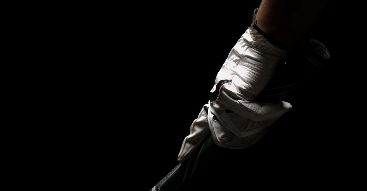 A close-up shot of a golfer's hand in a white glove gripping a golf club against a black background.